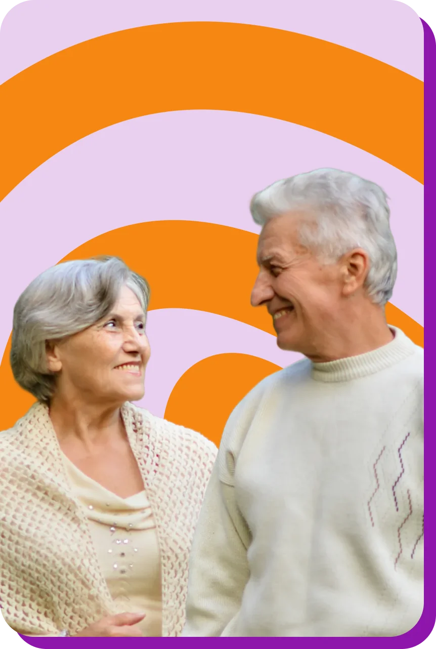 Smiling elderly couple in cozy sweaters against a colorful abstract background.