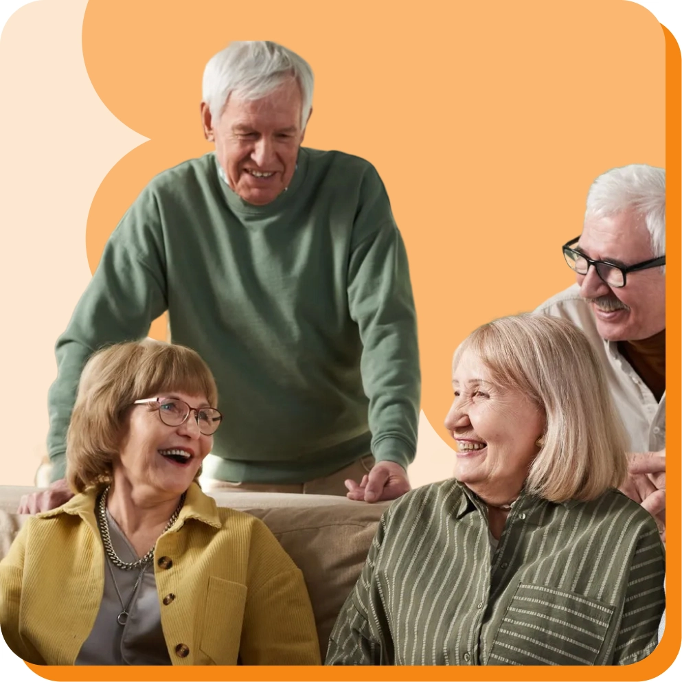 Elderly friends smiling and enjoying a conversation indoors with an orange background.