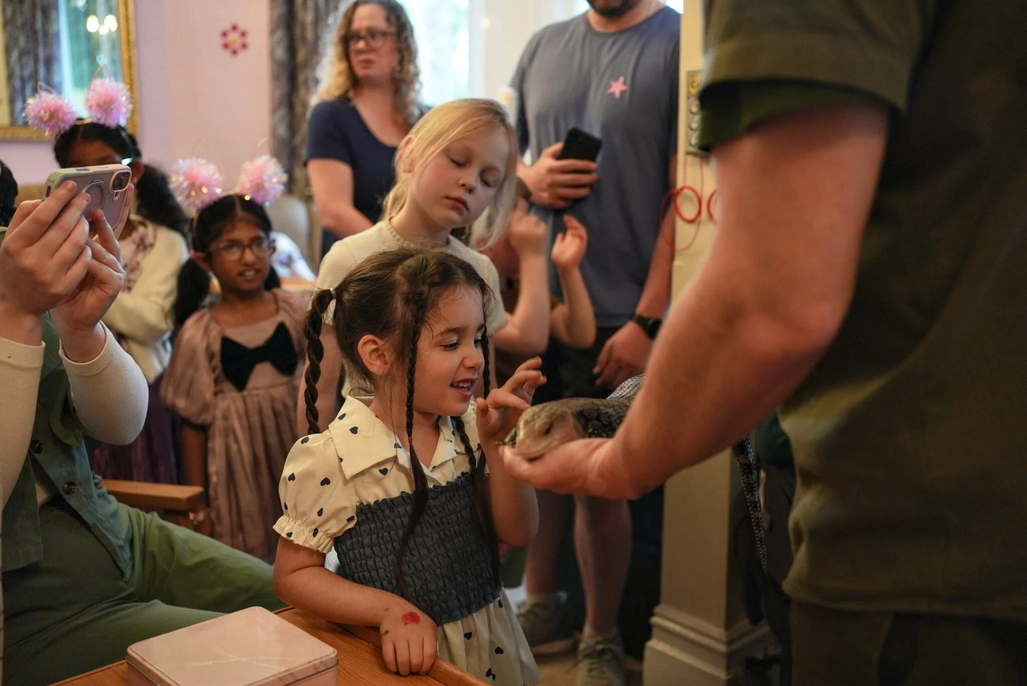 Children joyfully interact with small animal during an indoor educational event.
